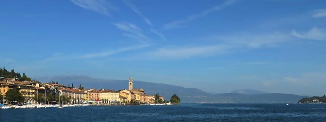 Trip Menorca beliebte Urlaubsziele am Gardasee -  Mit einer Fläche von 370 km² ist der Gardasee der größte See Italiens. Es liegt am Fuße der Alpen und erstreckt sich über drei Staaten: Lombardei, Venetien und Trentino. Die maximale Tiefe des Sees beträgt 346 m, er hat eine längliche Form und sein nördliches Ende ist sehr schmal. Dort ist der See von den Bergen der Gruppo di Baldo umgeben. Du trittst aus deinem gemütlichen Hotelzimmer und es begrüßt dich die warme italienische Sonne. Du blickst auf den atemberaubenden Gardasee, der in zahlreichen Blautönen schimmert - von tiefem Dunkelblau bis zu funkelndem Türkis. Majestätische Berge umgeben dich, während die Brise sanft deine Haut streichelt und der Duft von blühenden Zitronenbäumen deine Nase kitzelt. Du schlenderst die malerischen, engen Gassen entlang, vorbei an farbenfrohen, blumengeschmückten Häusern. Vereinzelt unterbricht das fröhliche Lachen der Einheimischen die friedvolle Stille. Du fühlst dich wie in einem Traum, der nicht enden will. Jeder Schritt führt dich zu neuen Entdeckungen und Abenteuern. Du probierst die köstliche italienische Küche mit ihren frischen Zutaten und verführerischen Aromen. Die Sonne geht langsam unter und taucht den Himmel in ein leuchtendes Orange-rot - ein spektakulärer Anblick.